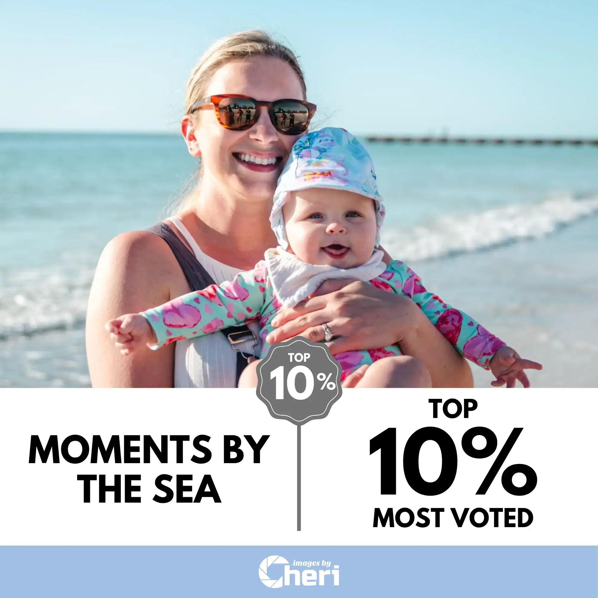 A smiling mother holding a laughing baby, both wearing hats and sunglasses, standing on a beach with the ocean waves behind them. Top 10% Most Voted.